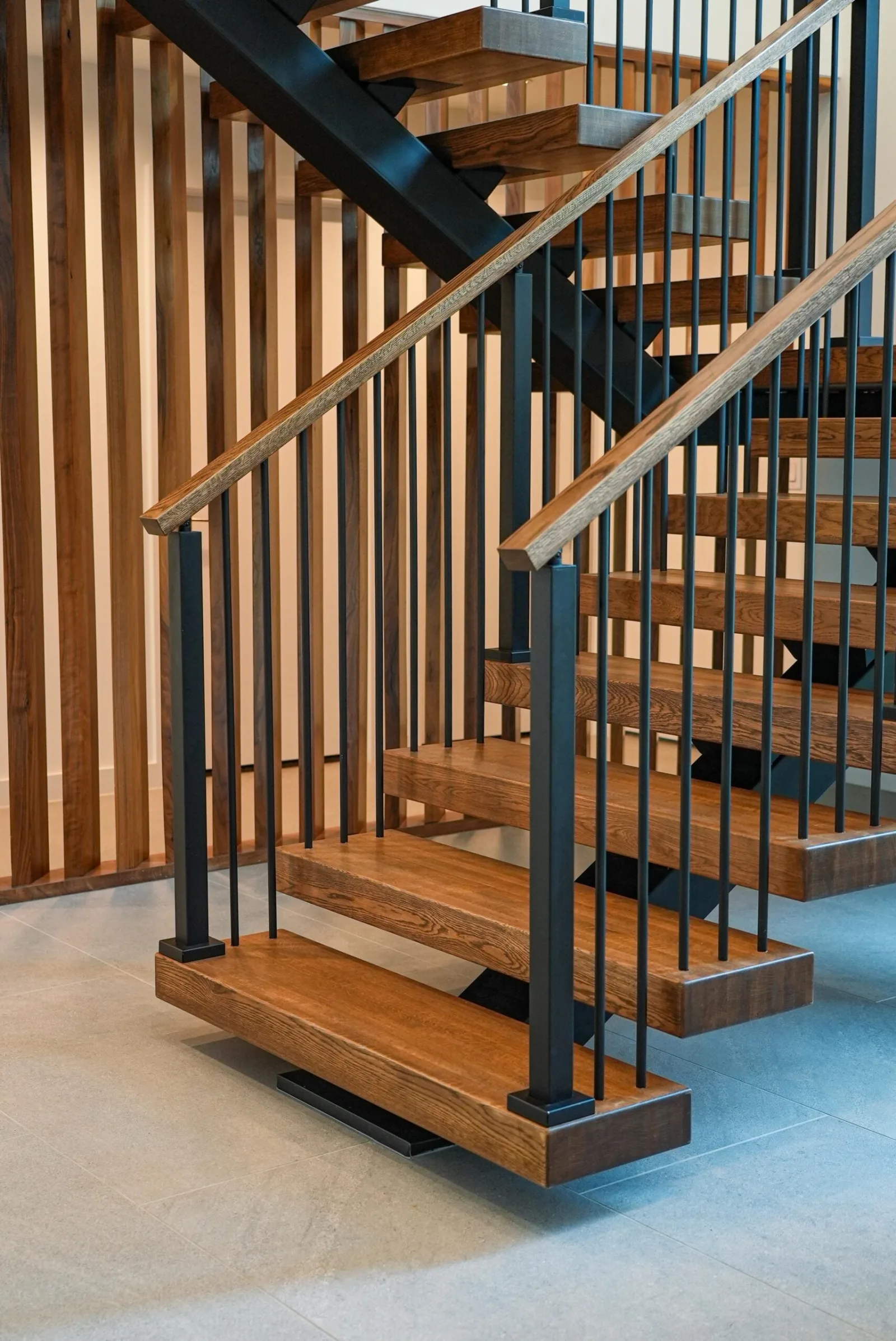 Full stair with black balusters rising beside a slatted wood wall