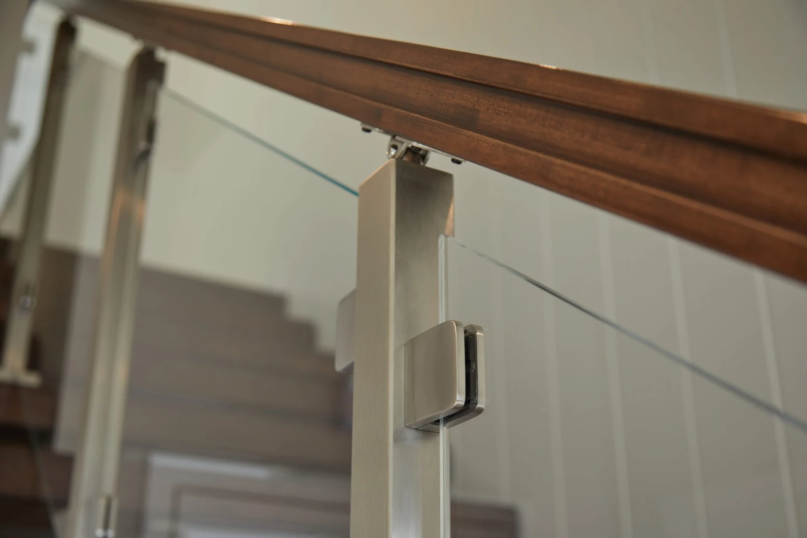 Close view of a stainless post clamping glass below a wood top rail