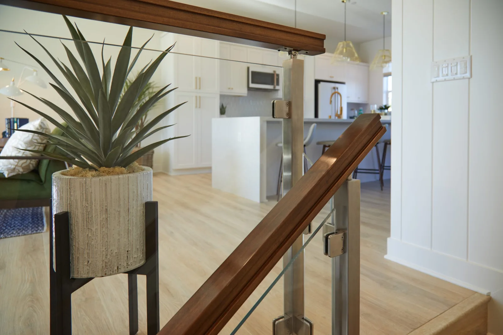 Wood top rail running along a balcony overlooking an open kitchen and living area