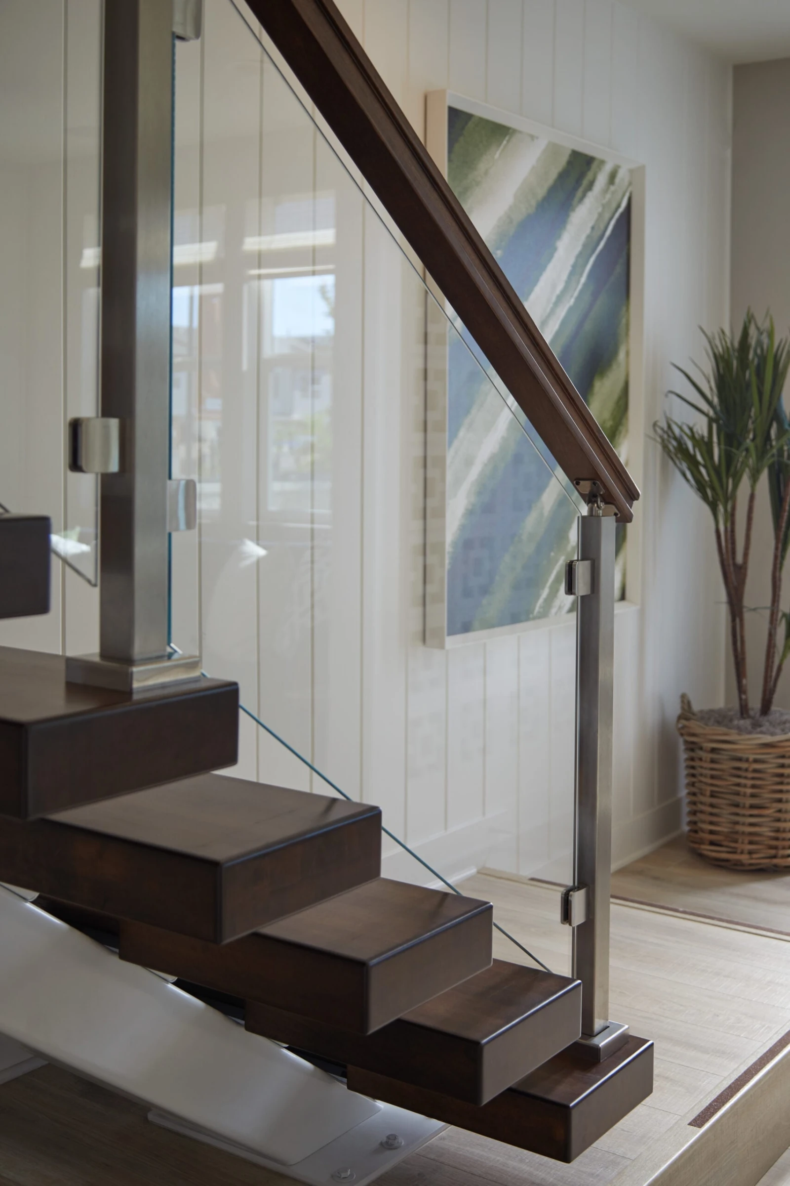 Glass railing and wood top rail seen from the landing above dark treads