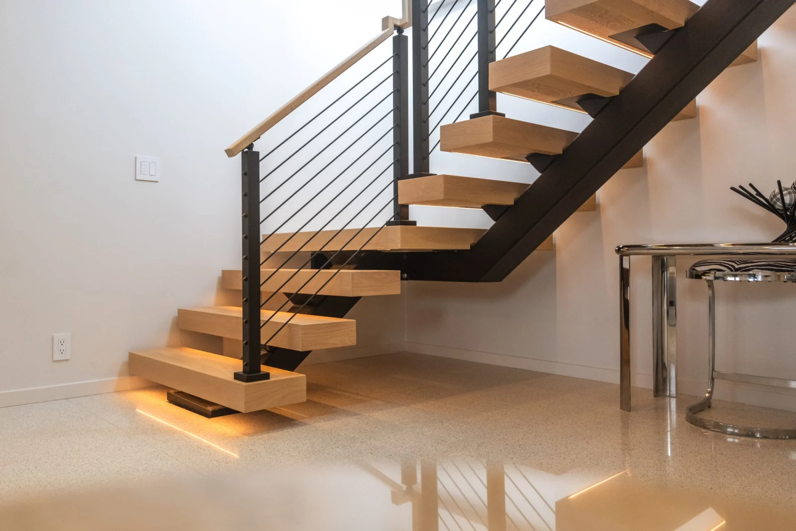Lit lower treads and a black center stringer seen from the room floor