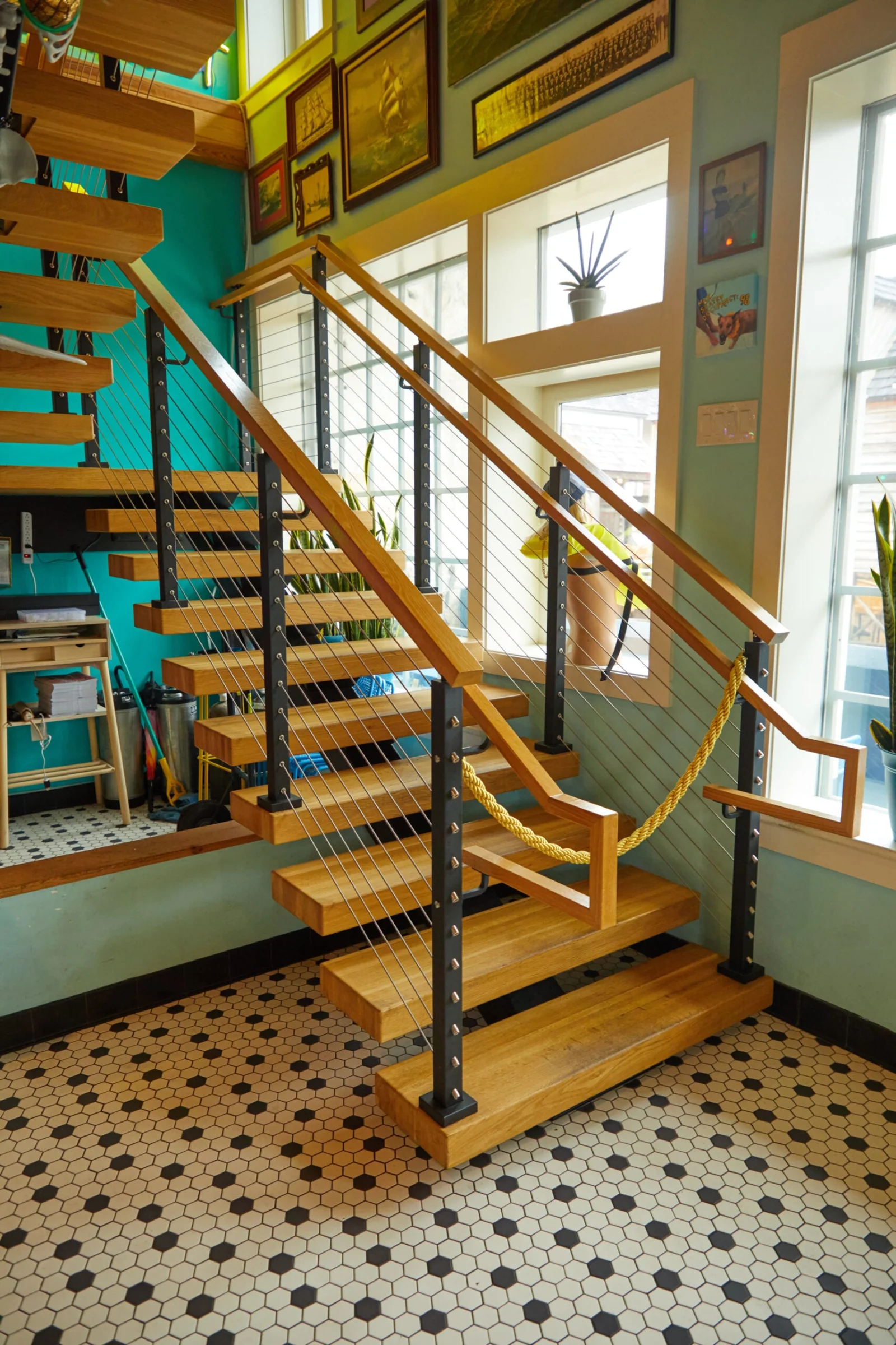 Cable railing and wood handrail at the stair base on patterned tile flooring