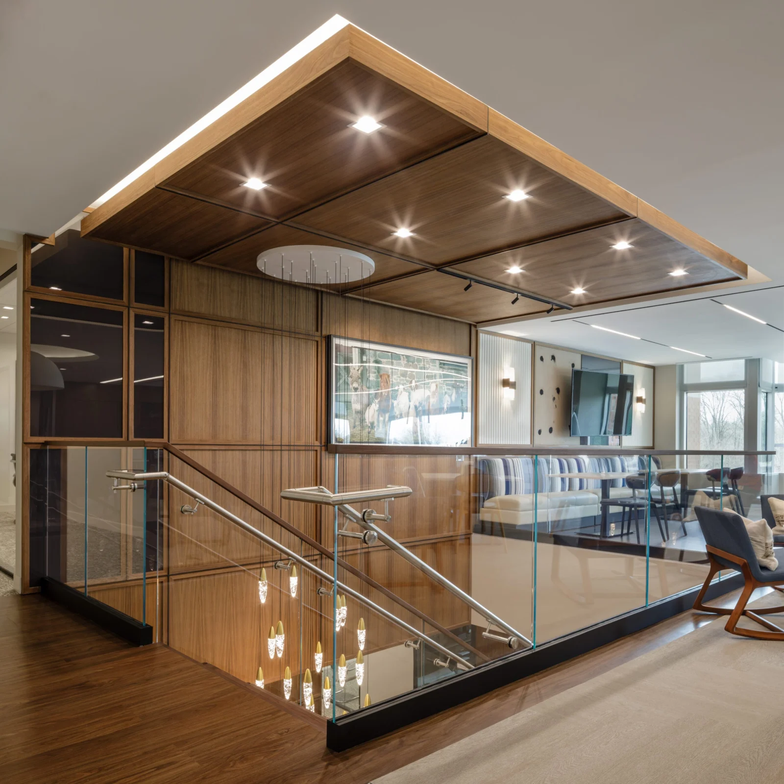 Wood clad ceiling and glass railing framing an office lounge on the upper level