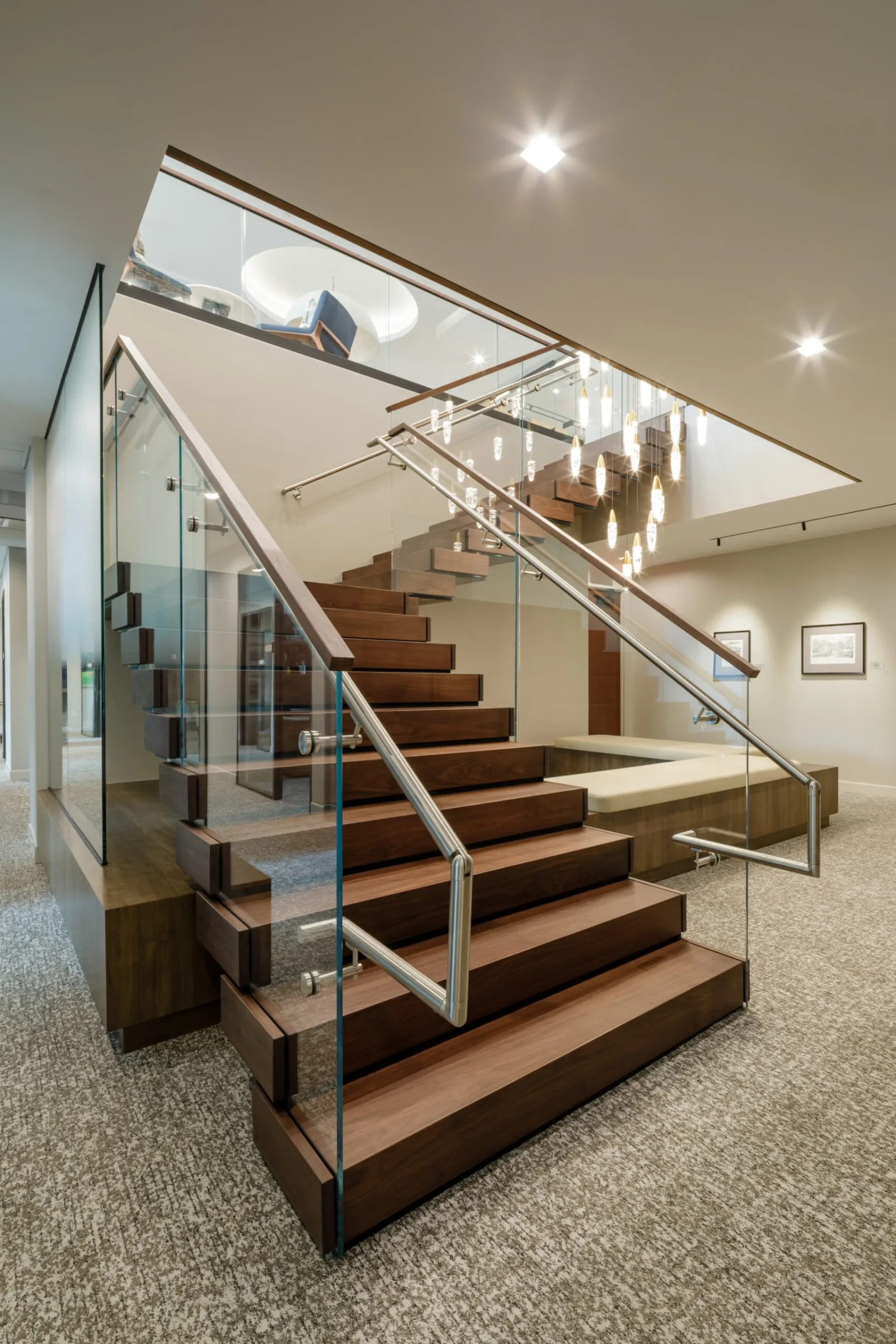 Dark wood stair with glass railing and stainless handrail in a carpeted lobby