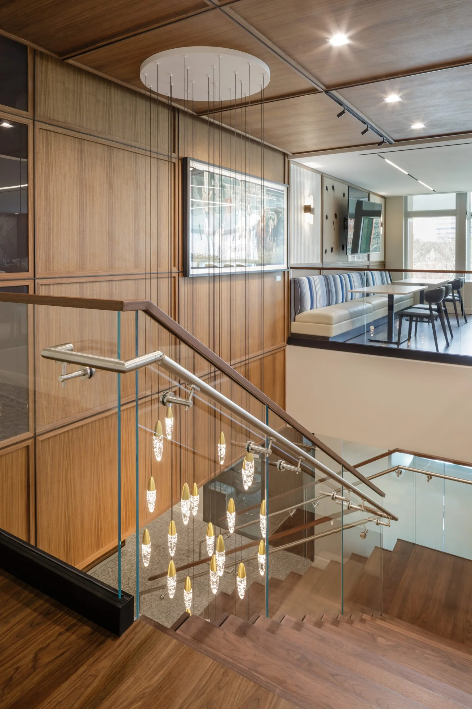 Pendant cluster dropping past the glass railing at the upper landing