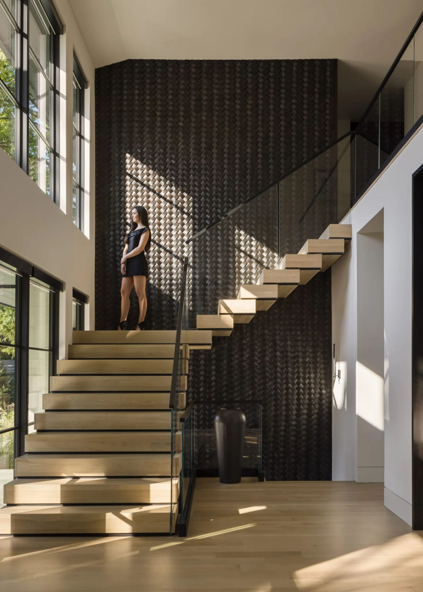 Pale stacked stair set against a dark textured wall with glass railing