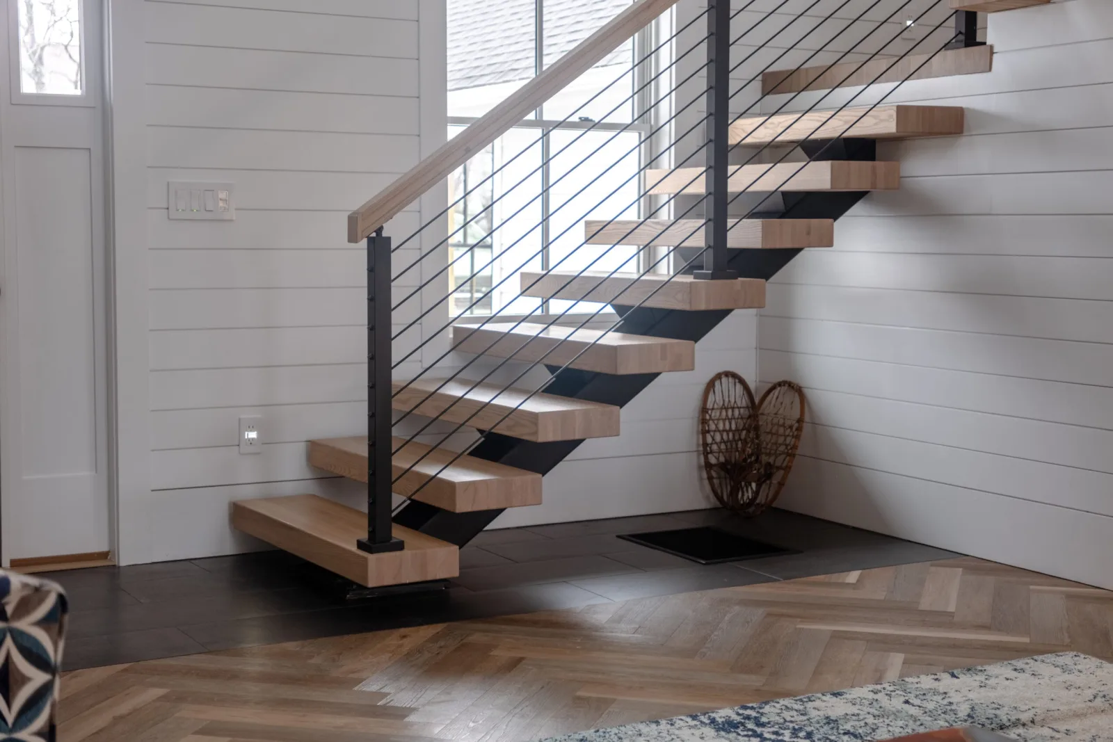 Full flight against shiplap with black single stringer, wood treads and rod railing