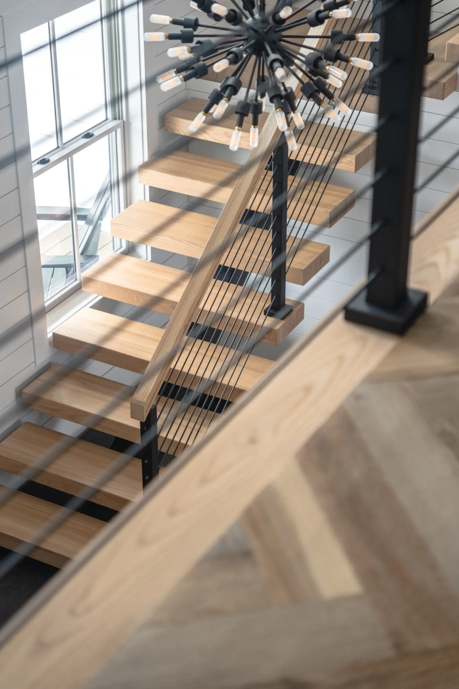 Overhead view through rod railing of the flight and a starburst pendant light