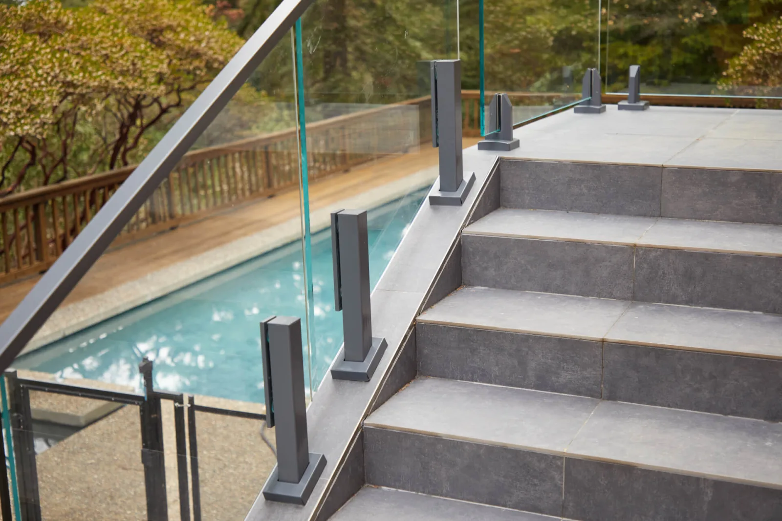 Stone stair with glass panels on charcoal base clamps climbing beside the pool