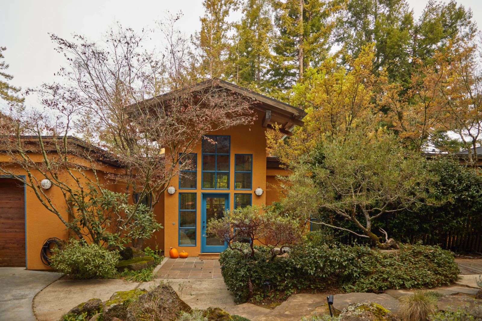Front entry of a stucco house with blue door under a peaked wood-framed porch