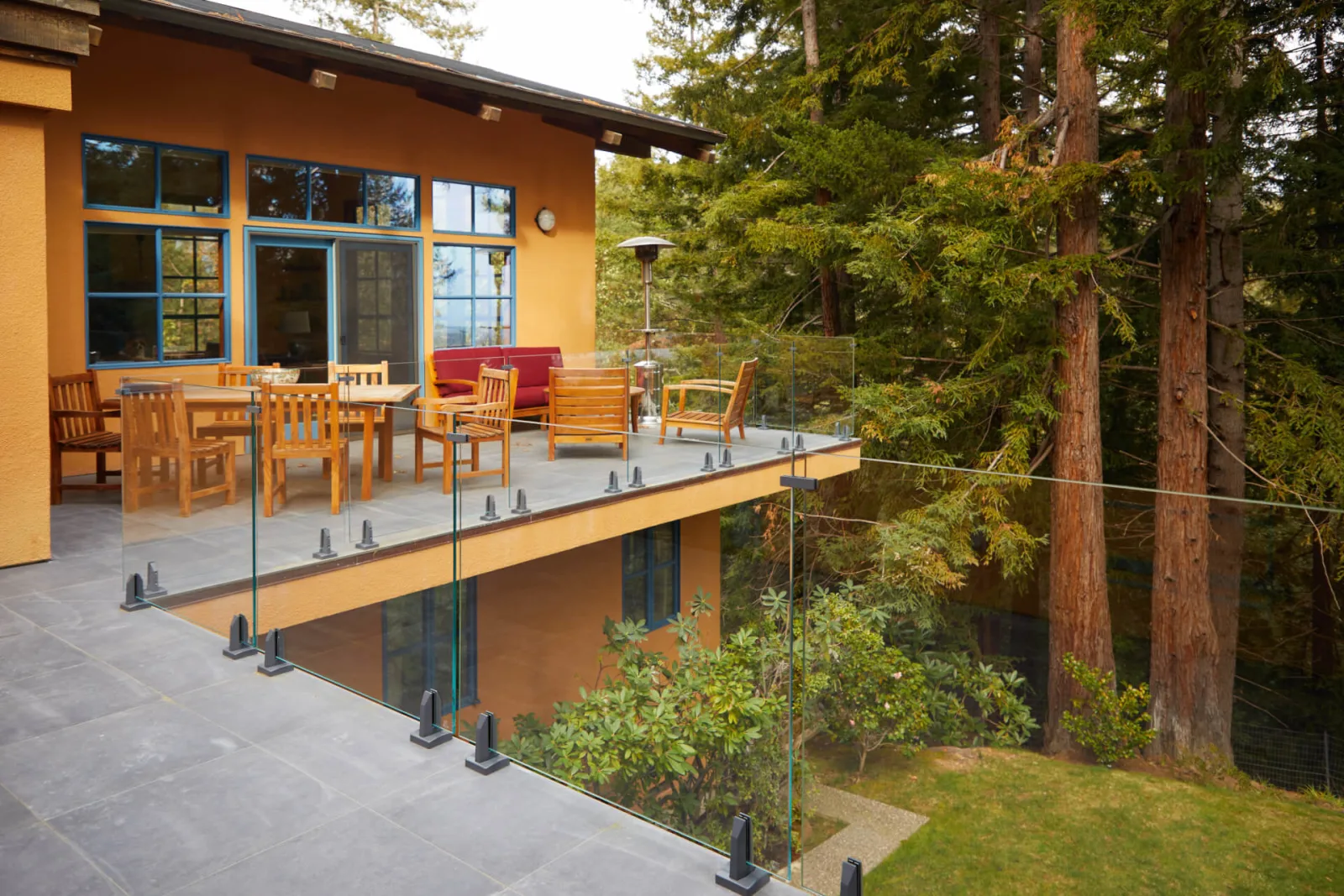 Terrace seating with glass railing wrapping the deck edge above the sloping yard