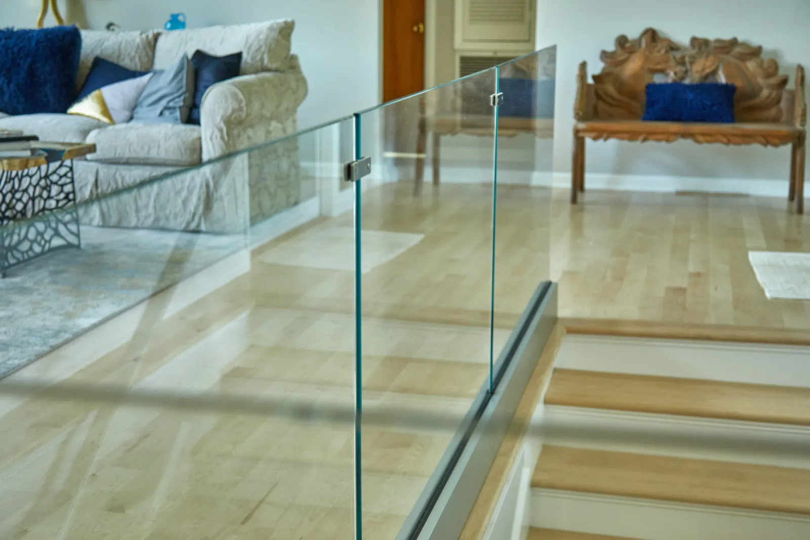 Glass railing panel guarding a stair opening beside a seating area