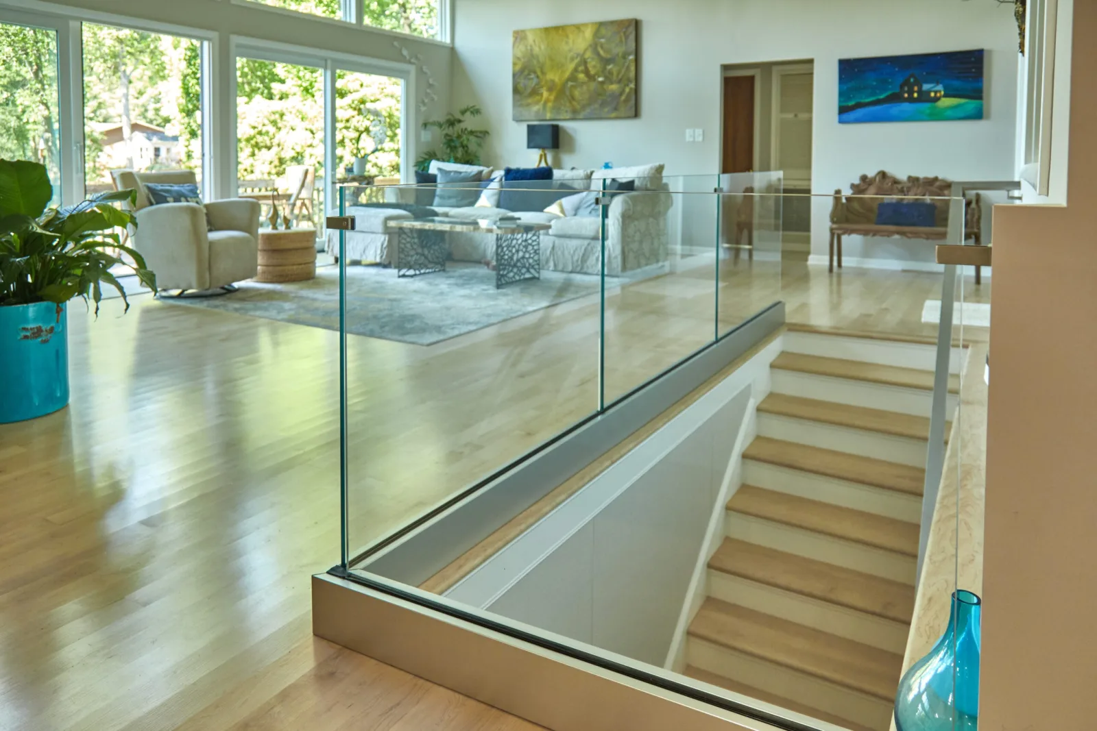 Living room with glass railing wrapping the stair well and a wood-capped return