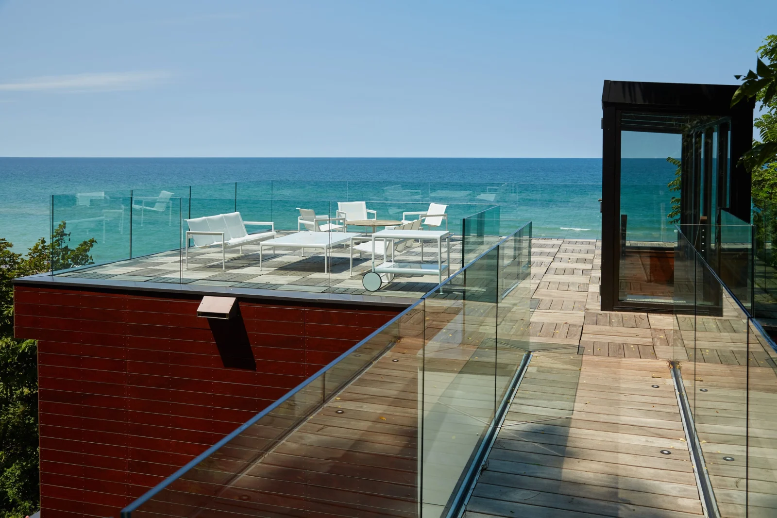 Rooftop deck above the lake with glass railing around lounge seating