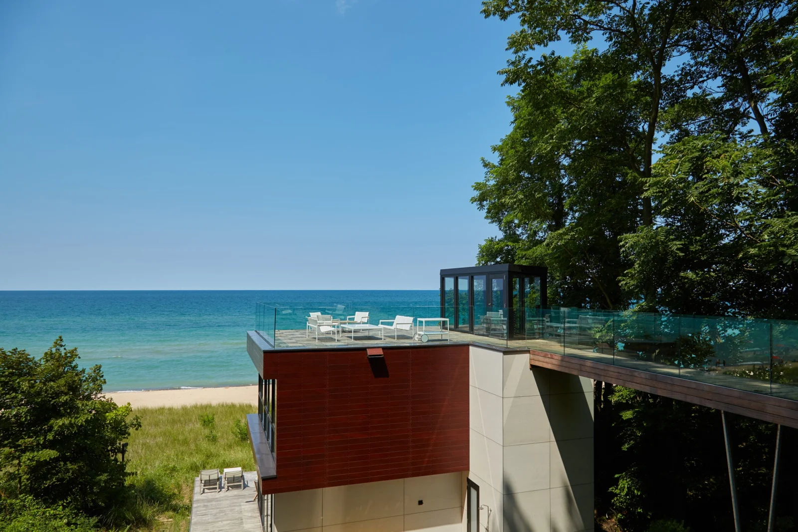 Long view over the beach with a glass-railed walkway leading to a rooftop terrace