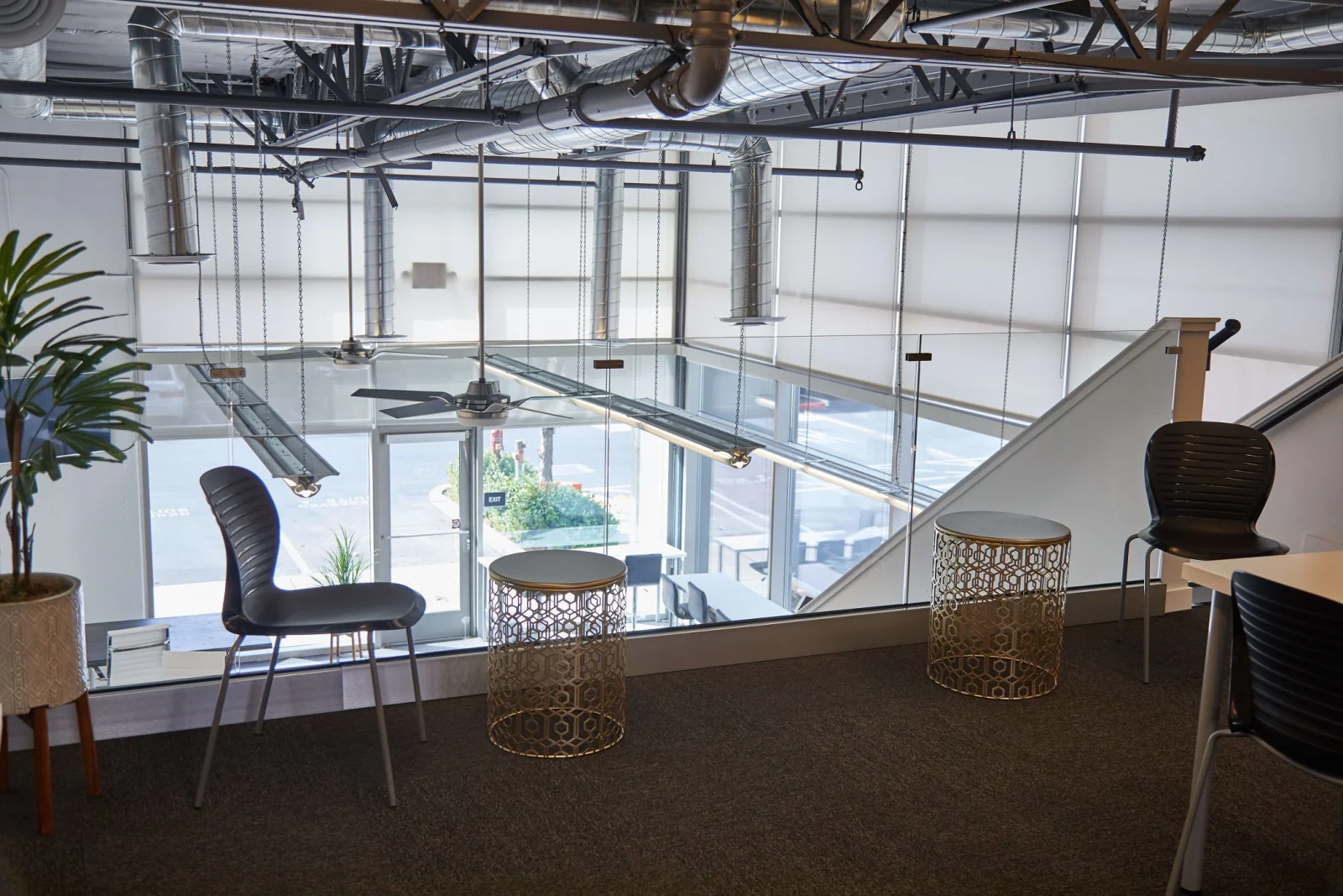 Office mezzanine with glass railing overlooking the floor and exposed ductwork