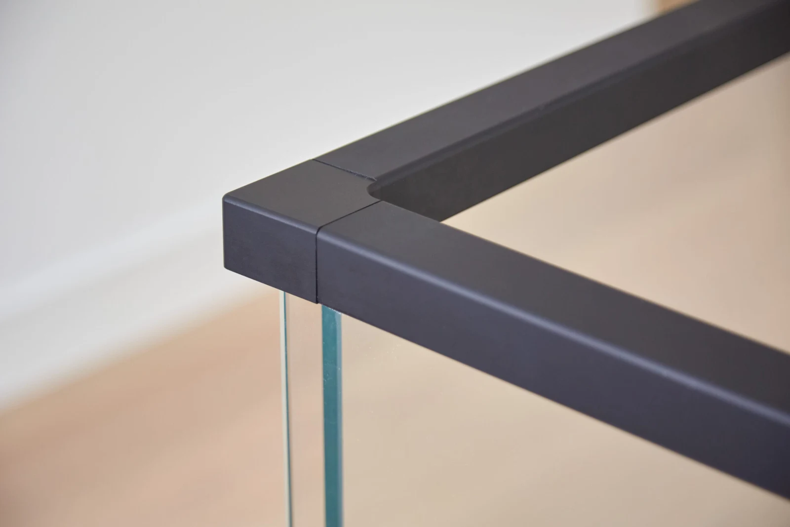 Corner detail of a black cap rail meeting glass panels at a balcony return