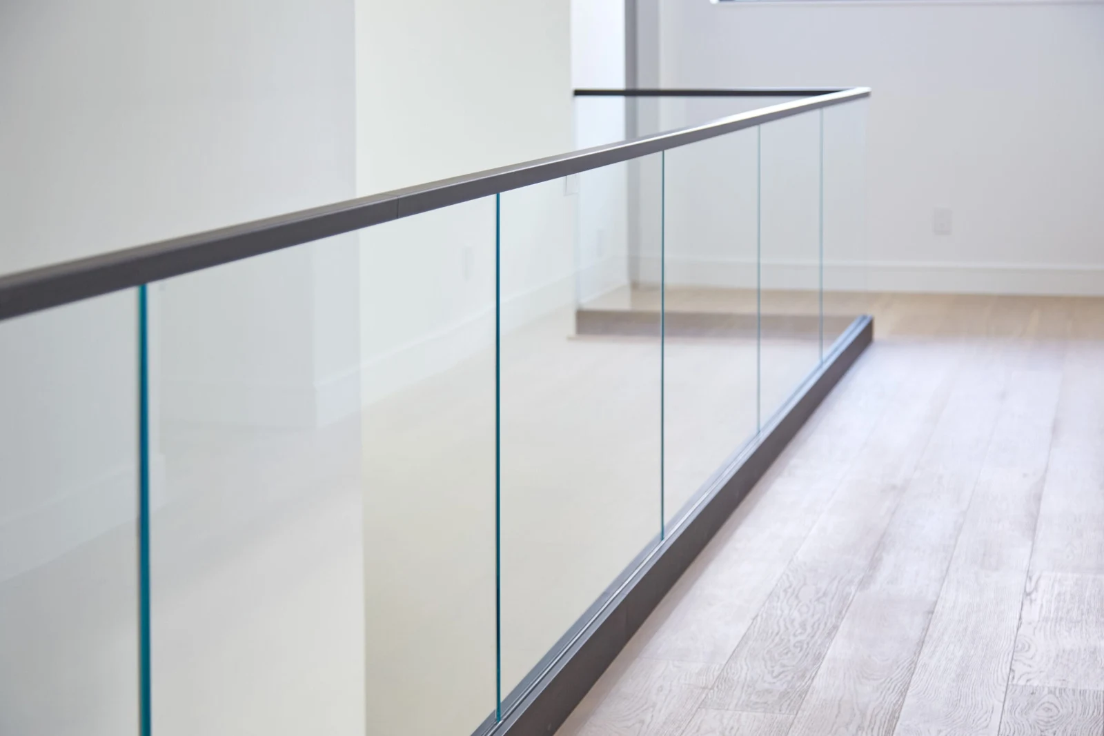 Balcony run of glass railing with black cap rail and matching base shoe