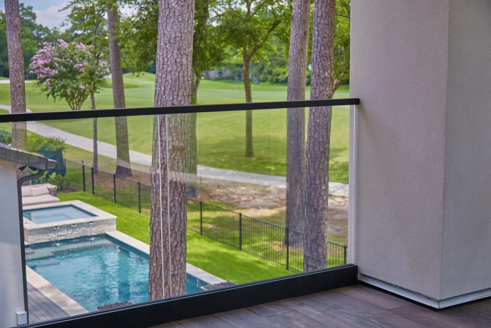 Balcony glass railing with a pool and fairway visible through the clear panels