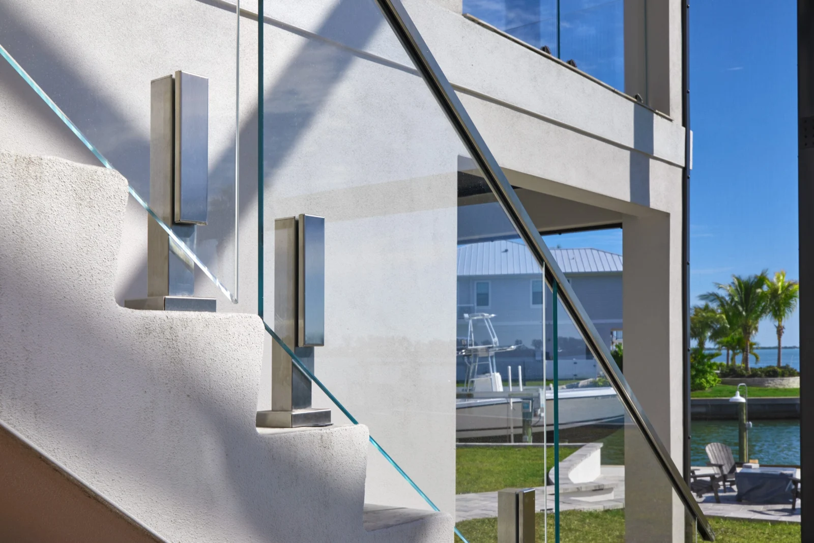 Stainless standoffs hold glass along a white stair wall near the waterfront