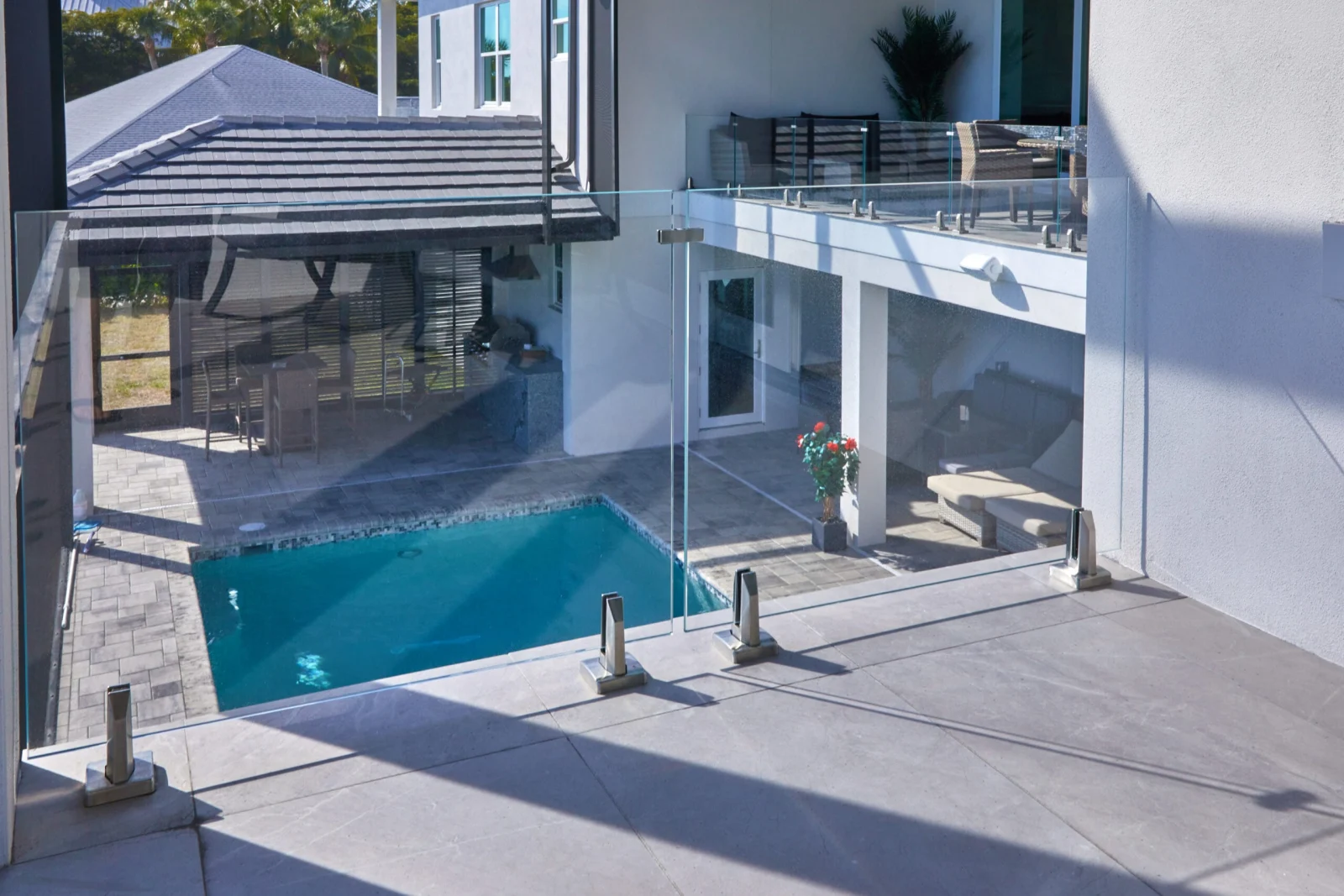 Courtyard pool enclosed by glass panels in stainless base clamps beside the house