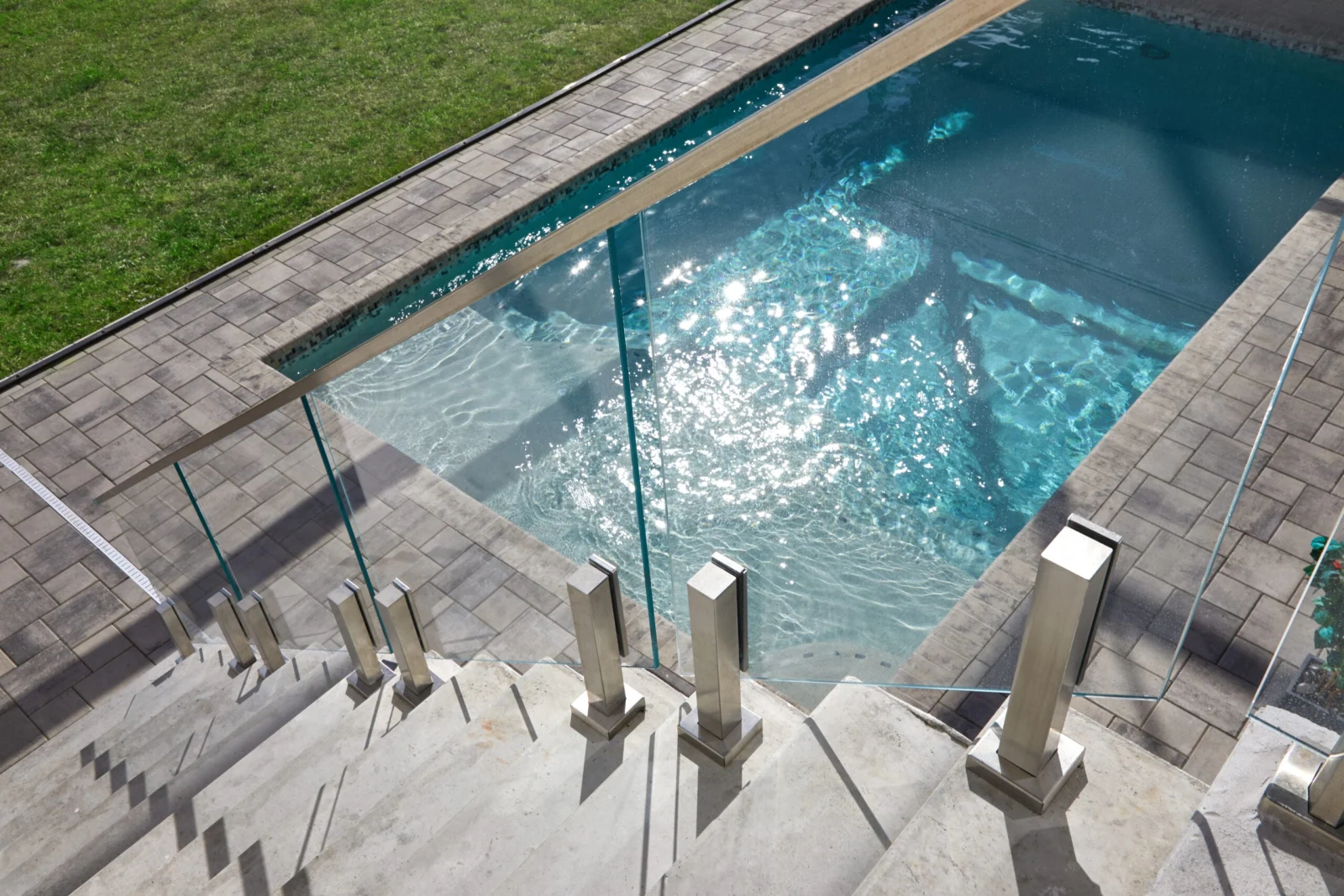 Aerial angle on pool steps where stainless posts carry frameless glass panels