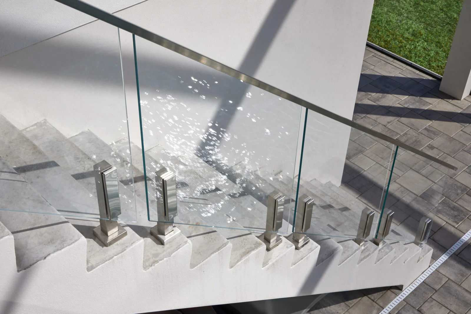 Looking down concrete steps lined with stainless posts and clear glass panels