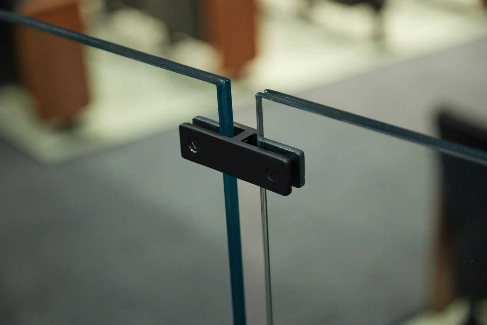 Close look at a black clip joining two glass panels under a slim rail