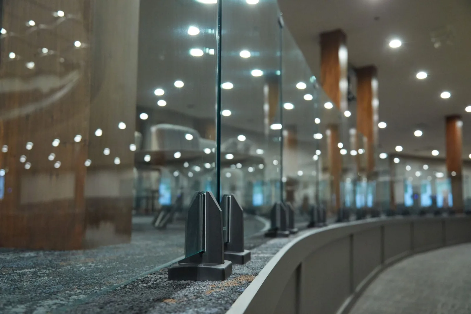 Low angle down a row of black spigots with ceiling lights in the glass