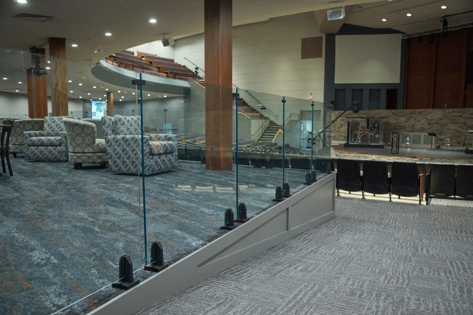 Church gathering space where glass railing on black spigots separates lounge from stairs