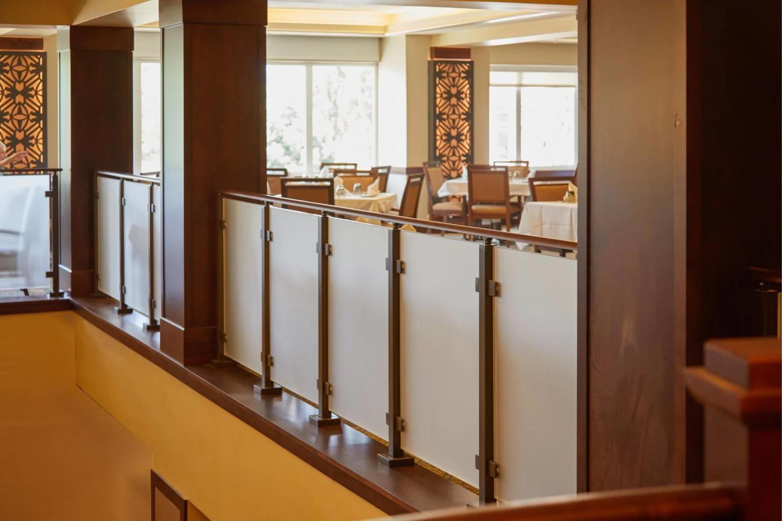 Frosted glass panels set in dark wood balcony framing above a warmly lit dining room