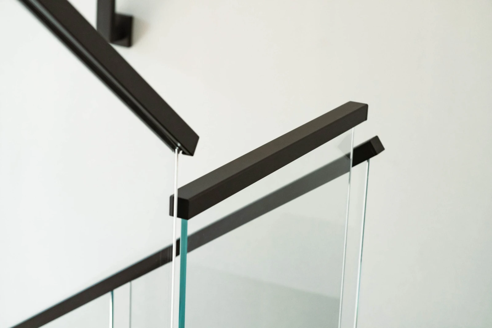 Black top rail turning a corner where two glass panels meet at the landing