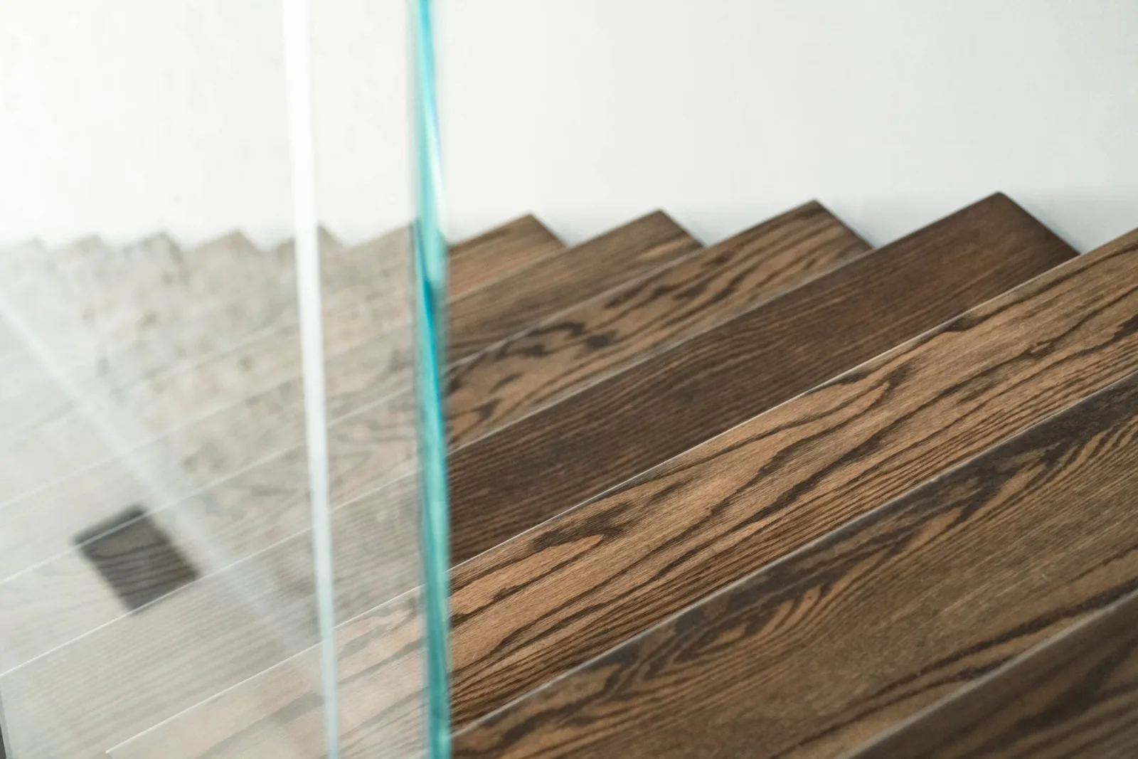 Glass panel edge cuts across dark treads with a pale wall behind