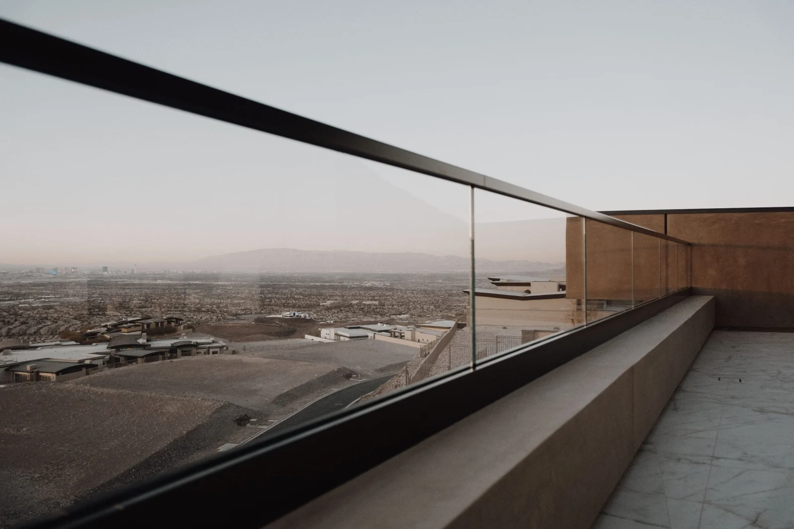 View along the railing's dark top rail toward desert valley and distant mountains