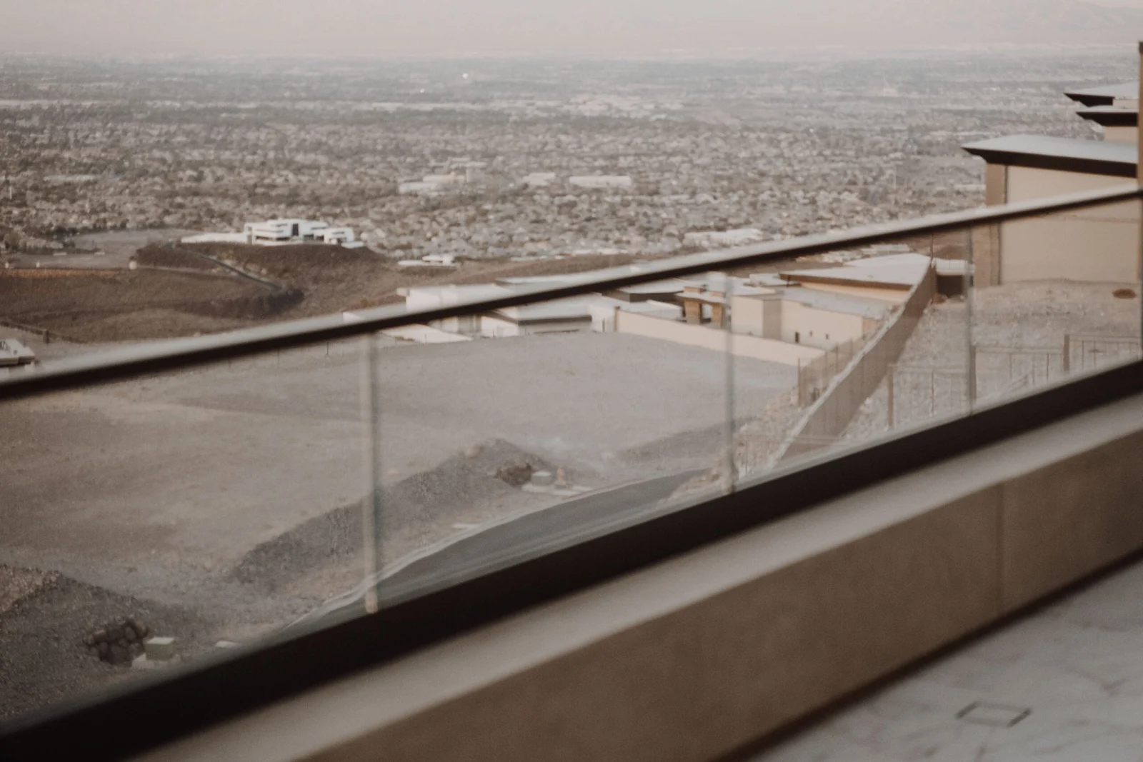 Curved run of glass panels wrapping a terrace above a sprawling valley of rooftops