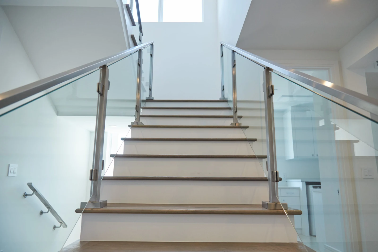 Straight flight climbing between glass panels on both sides with wood treads