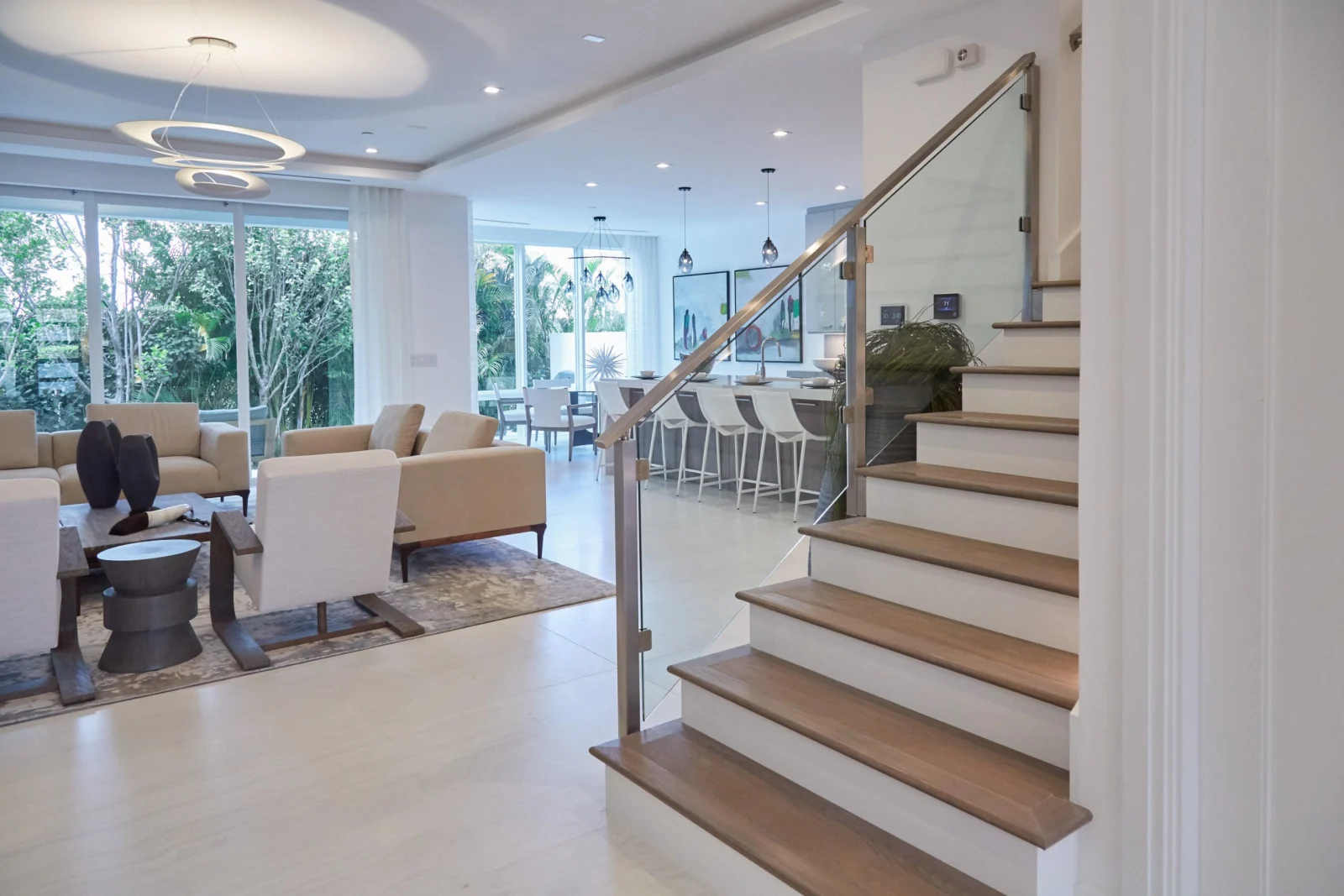 Open living room seen past a glass stair railing with a metal top rail