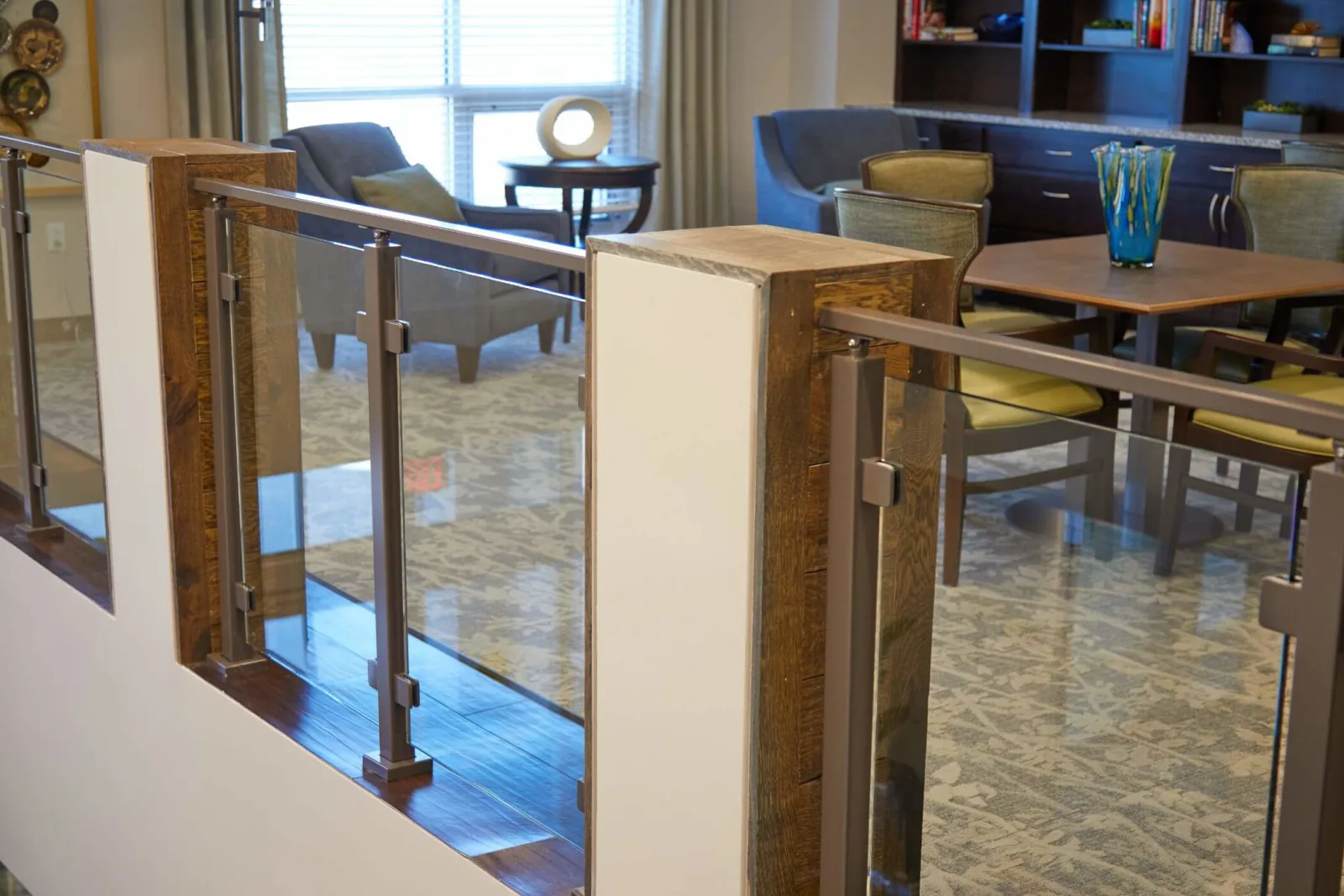 Glass railing sections set between wood-clad columns beside a common seating area