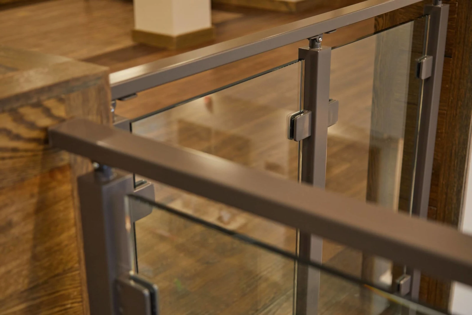 Angled detail of the top rail turning a corner above clamped glass panels