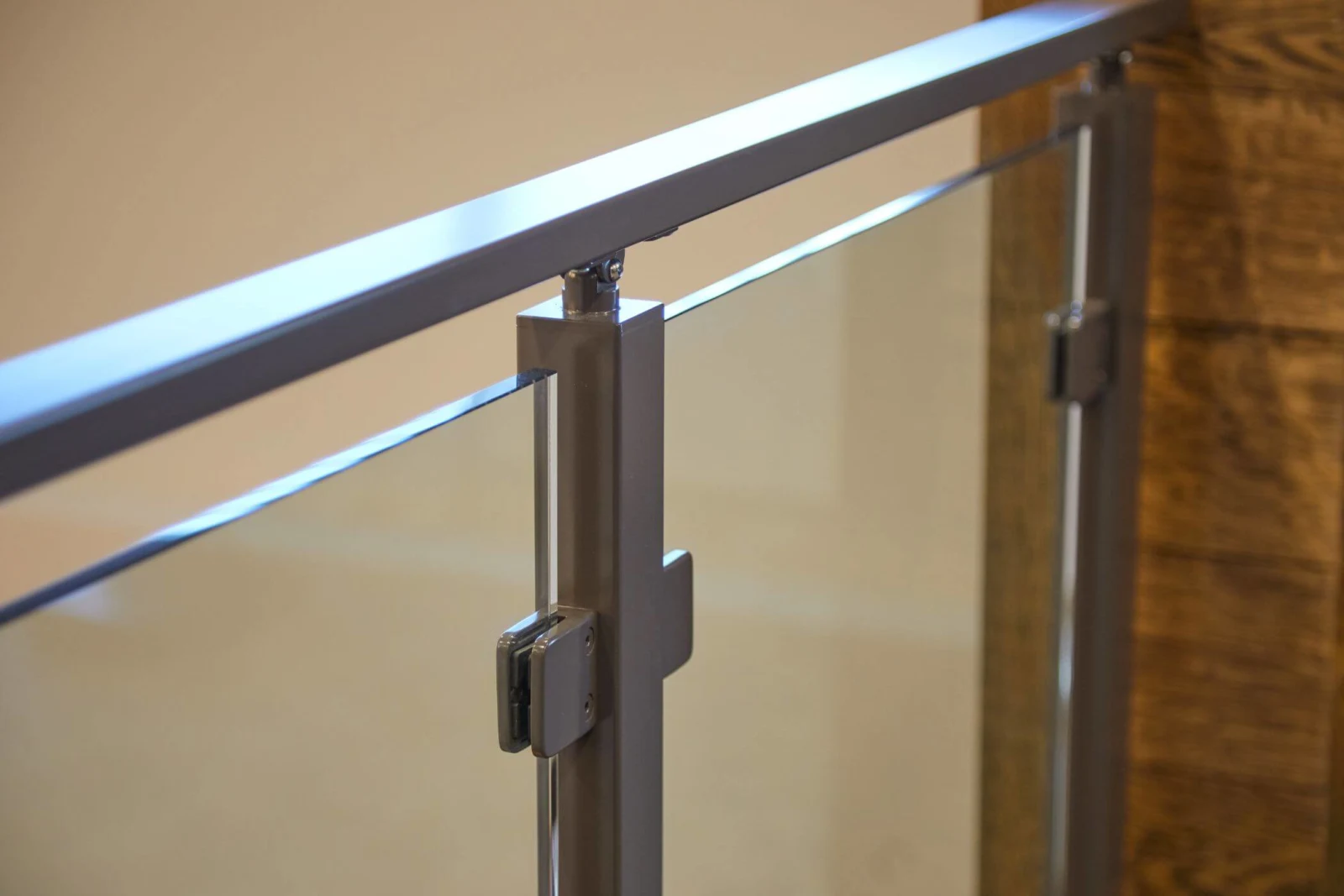 Brushed post and clamp hardware caught in raking light beside a wood column