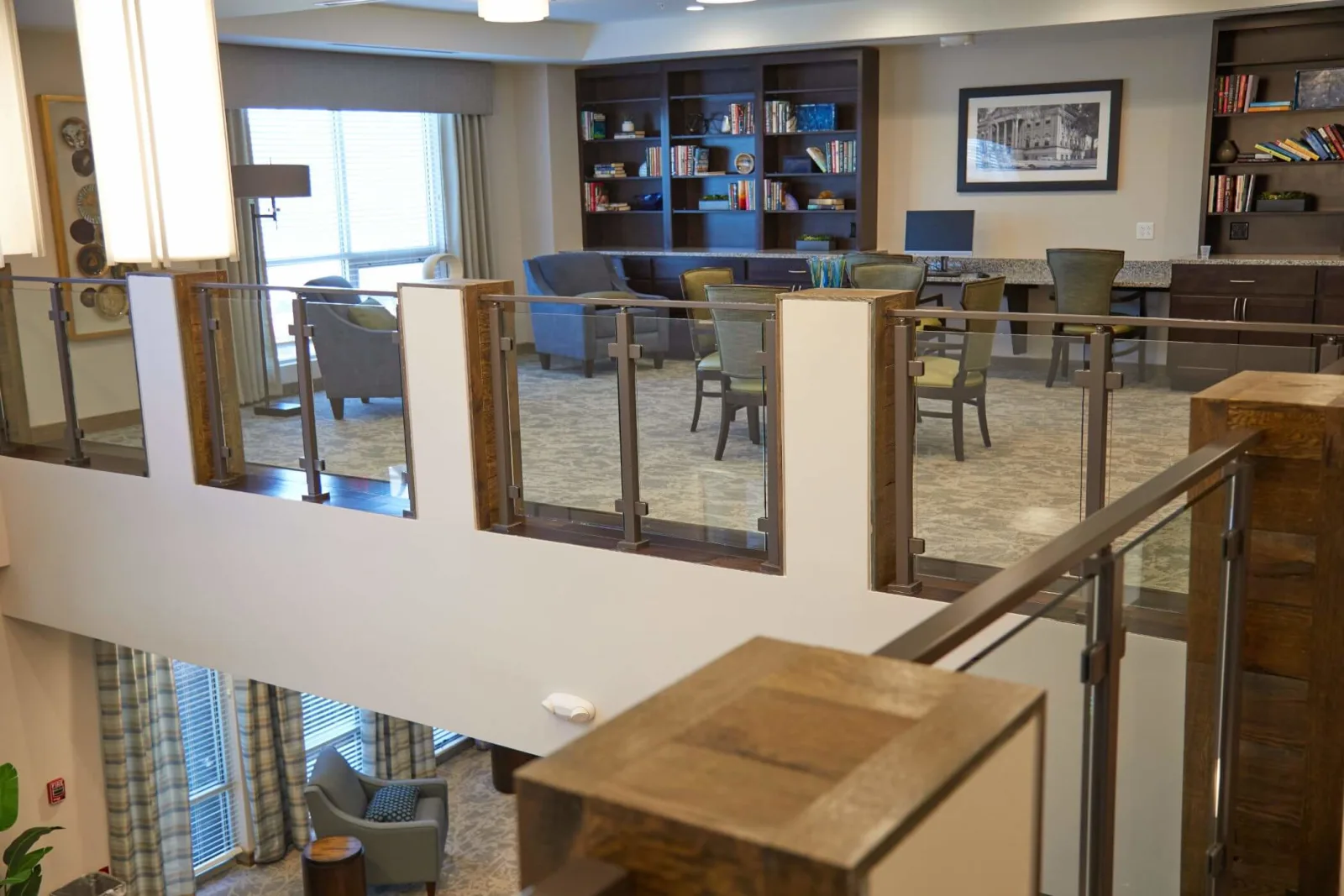 Overlook railing framing a library lounge with bookshelves and armchairs below