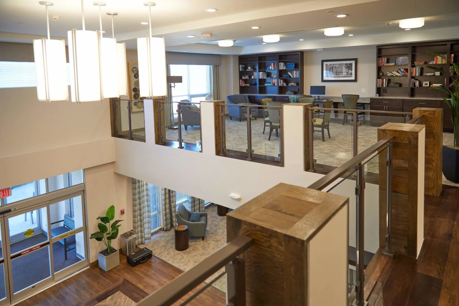 Pendant lights hanging beside an overlook railing above a two-level common room