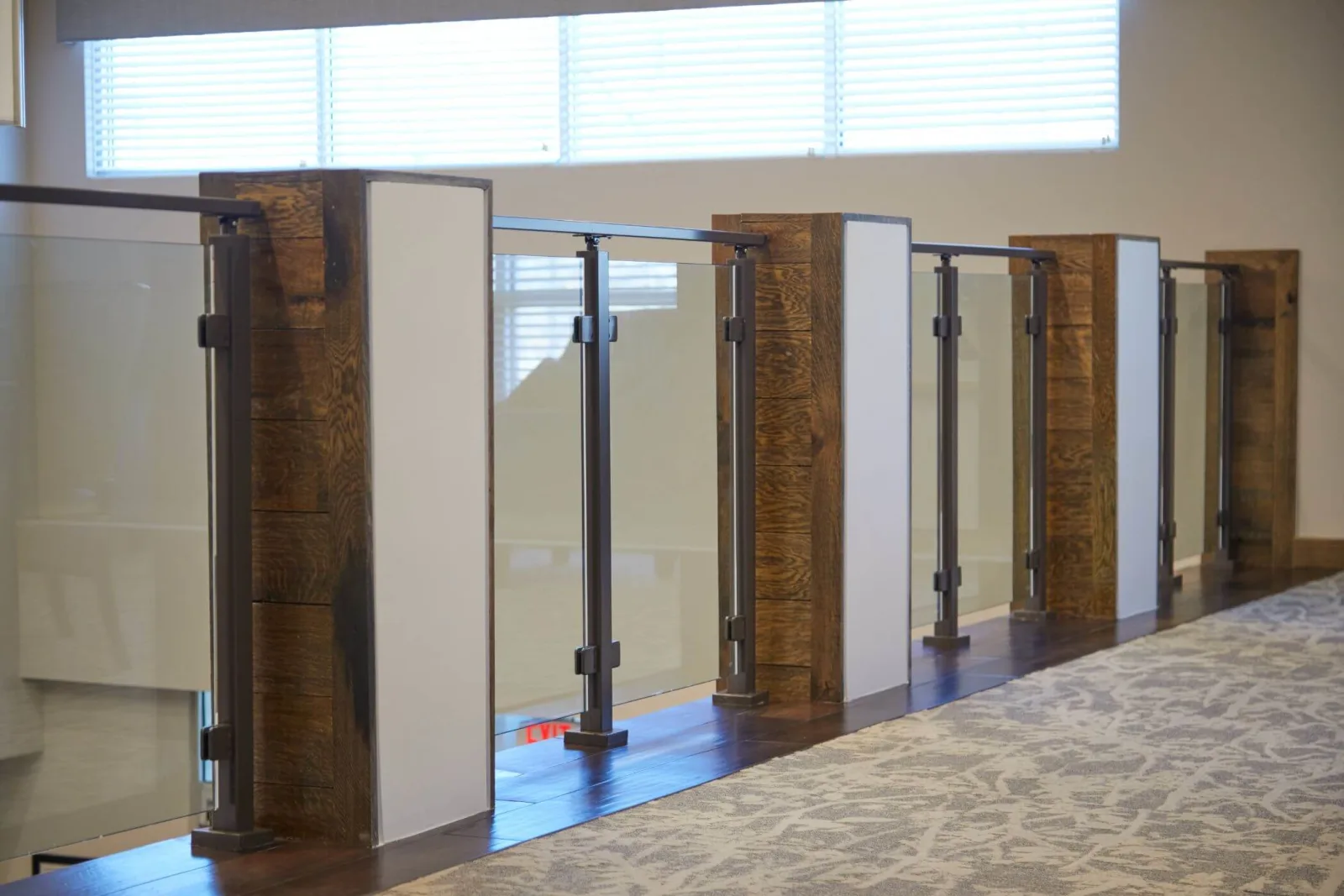 Heavy timber posts alternate with glass panels guarding a carpeted mezzanine edge