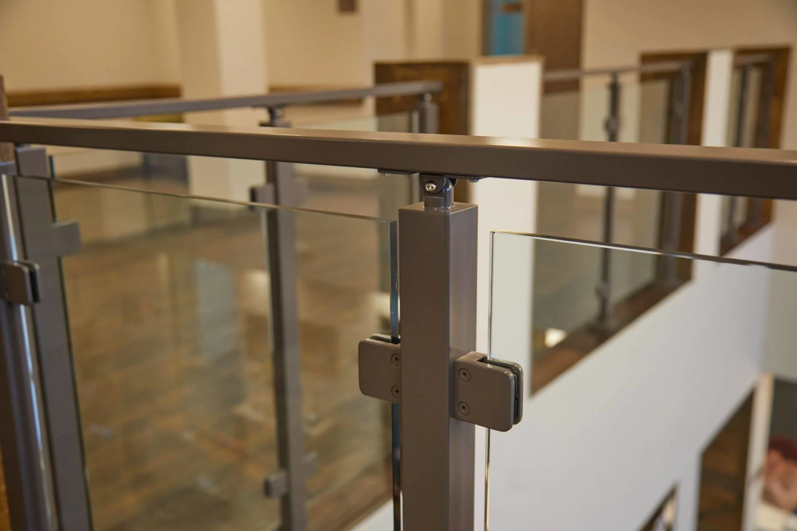 Bronze post and glass clamps in focus with the railing run receding behind