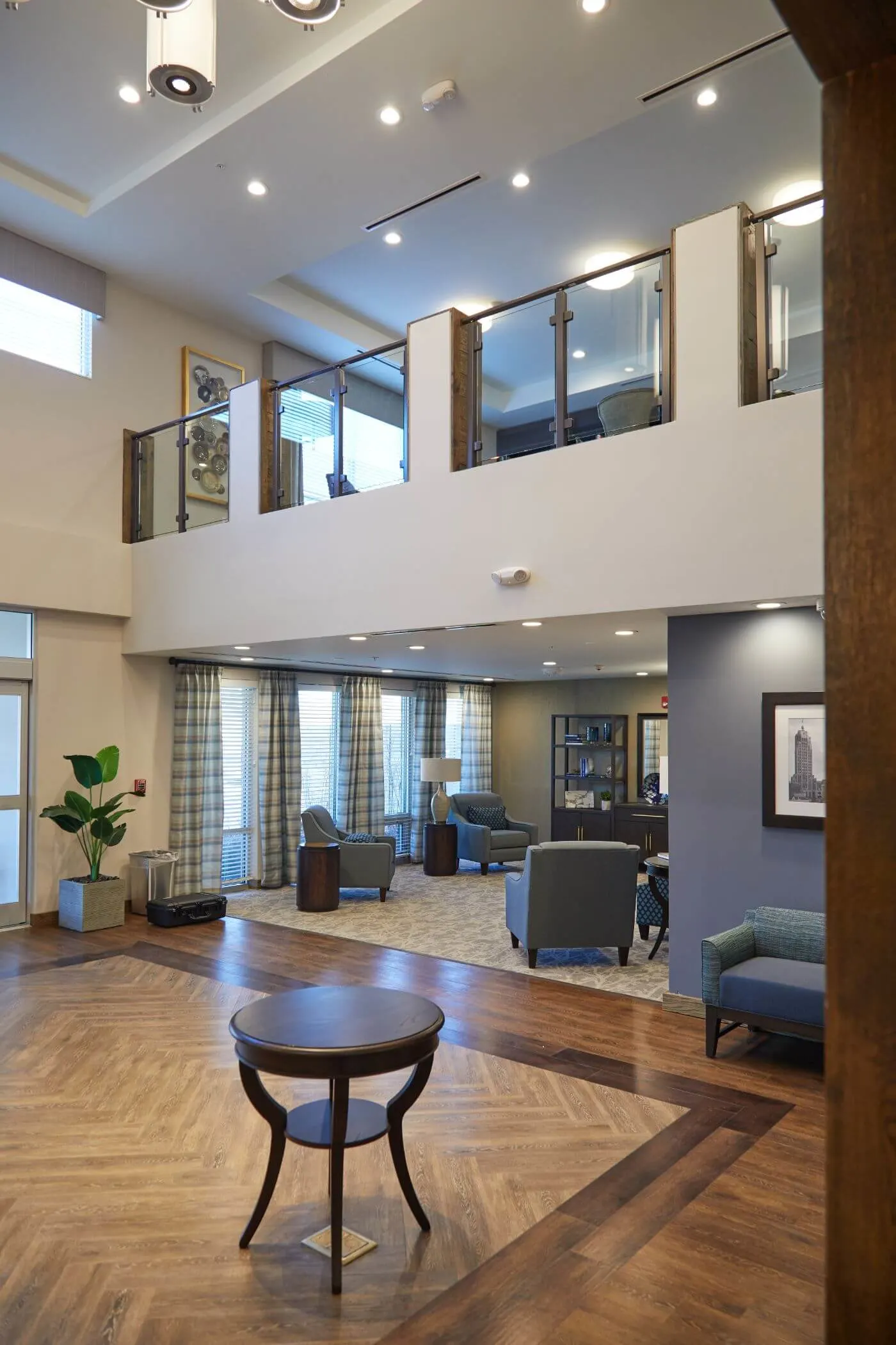 Two-level lobby with the balcony railing running above patterned wood flooring