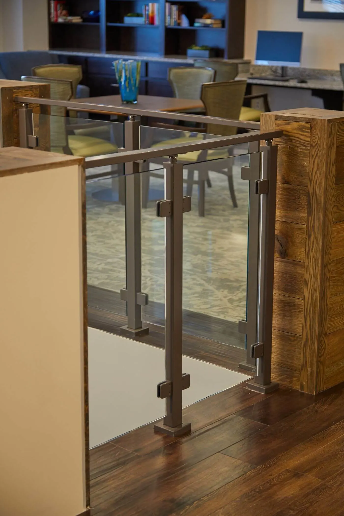 Railing corner meeting a wood-wrapped column above dark plank flooring