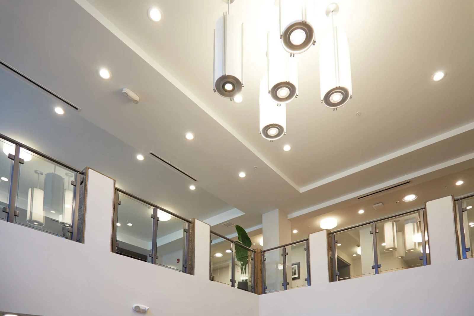 Sculptural ceiling fixtures above glass railing panels ringing the open second level