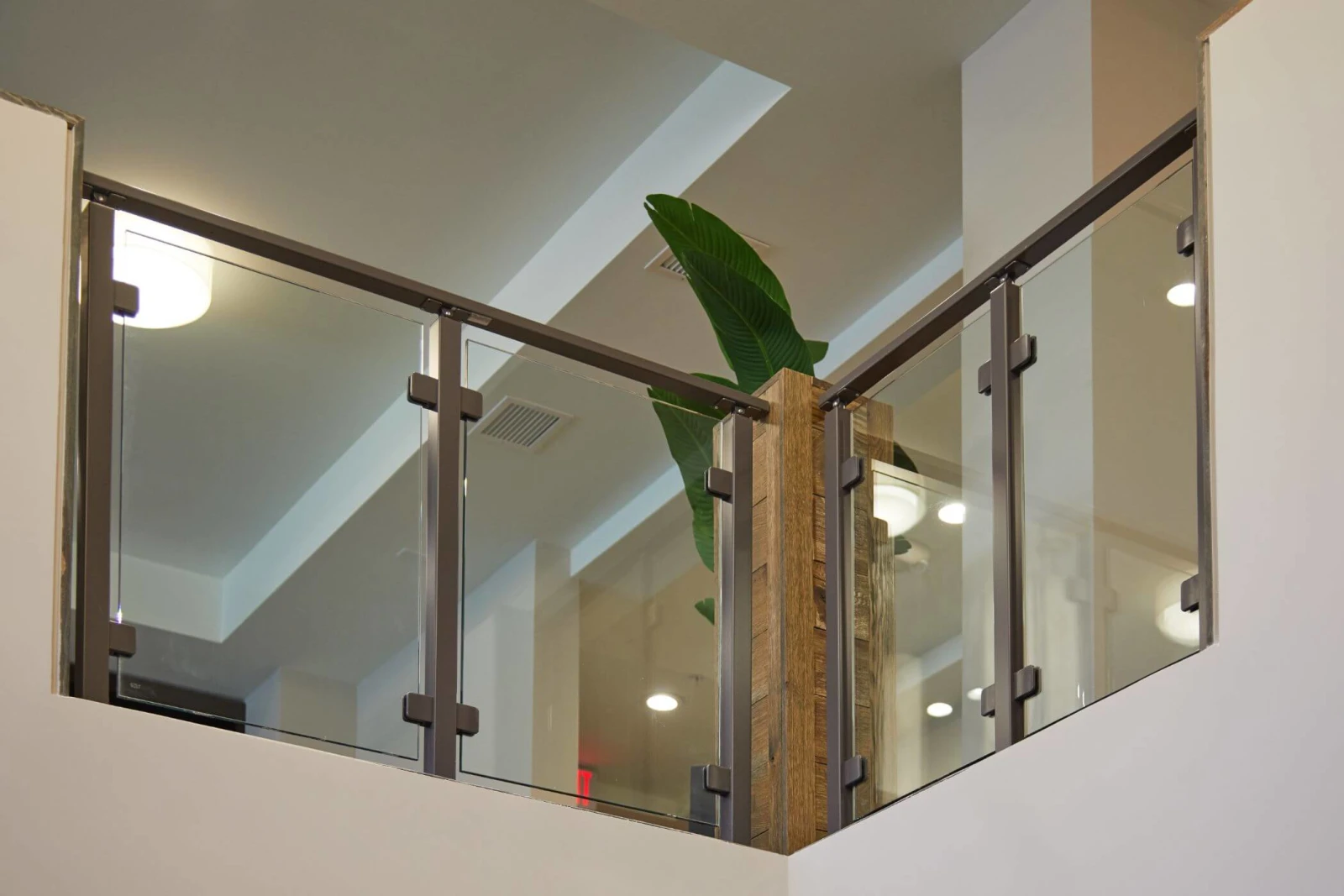 Glass railing meeting at an inside corner beside a reclaimed timber post