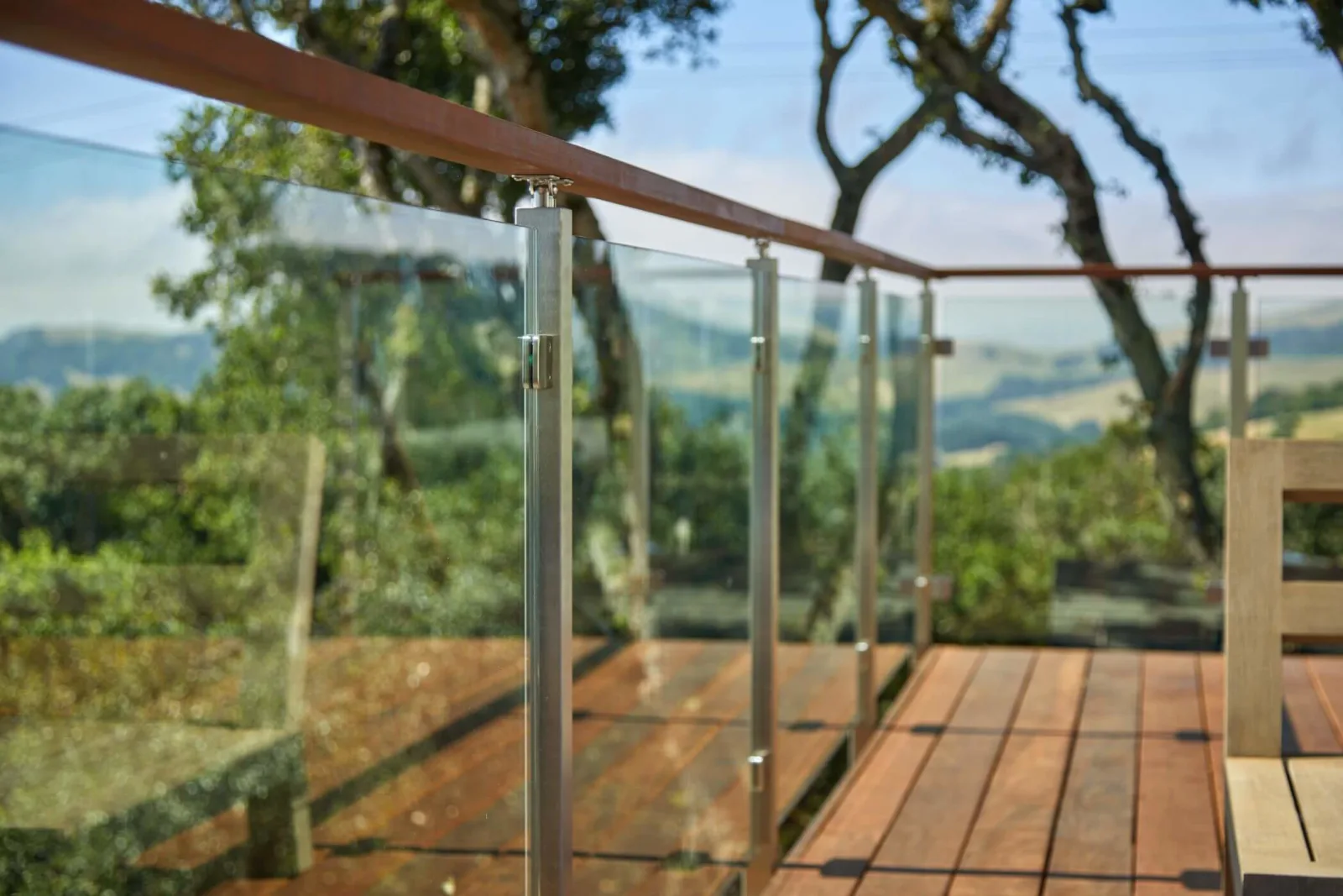 Angled view along the railing showing slim posts clamping each glass panel