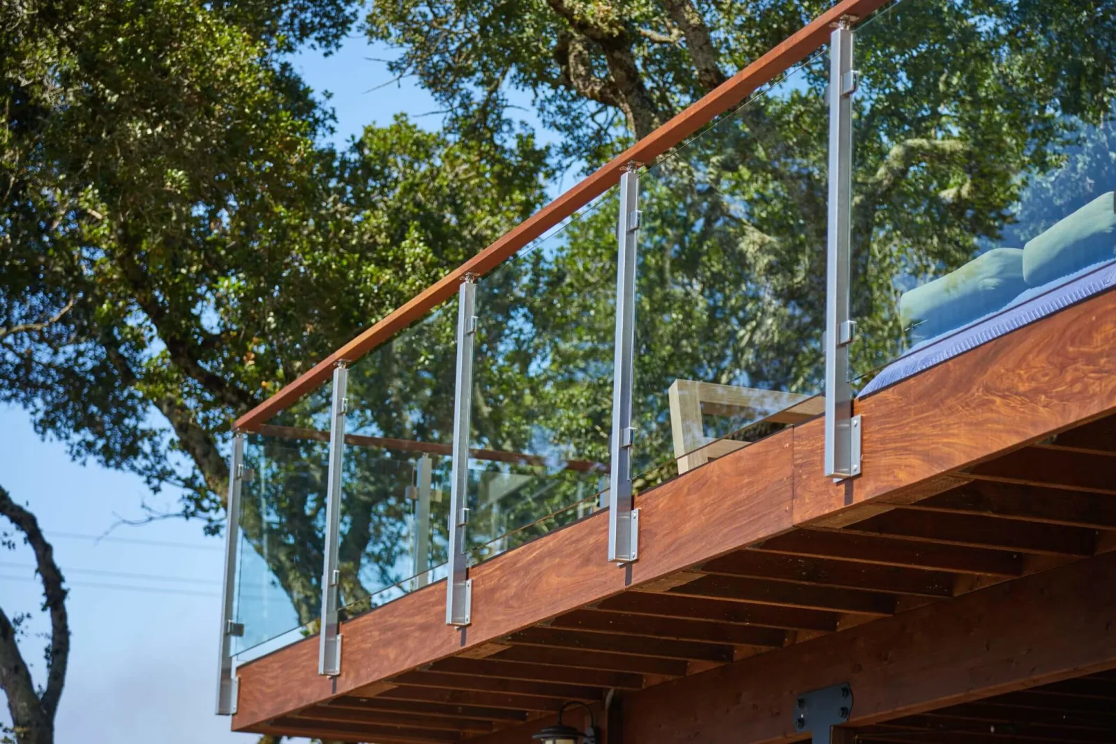 Seen from below, glass panels in metal posts with a wood top rail edge a deck